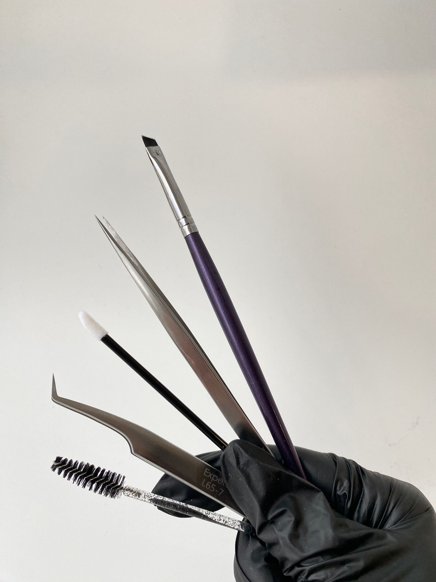 Brow shaping tools laid out on a gloved hand